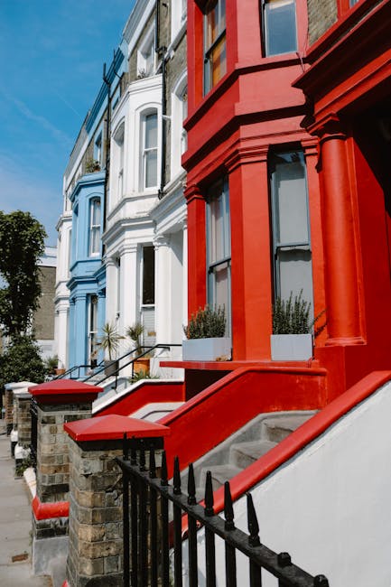 The image shows a narrow, two-storey green brick building with white window frames and signage reading 'Notting Hill Garage' on the front facade, situated on a residential street in Notting Hill. Adja